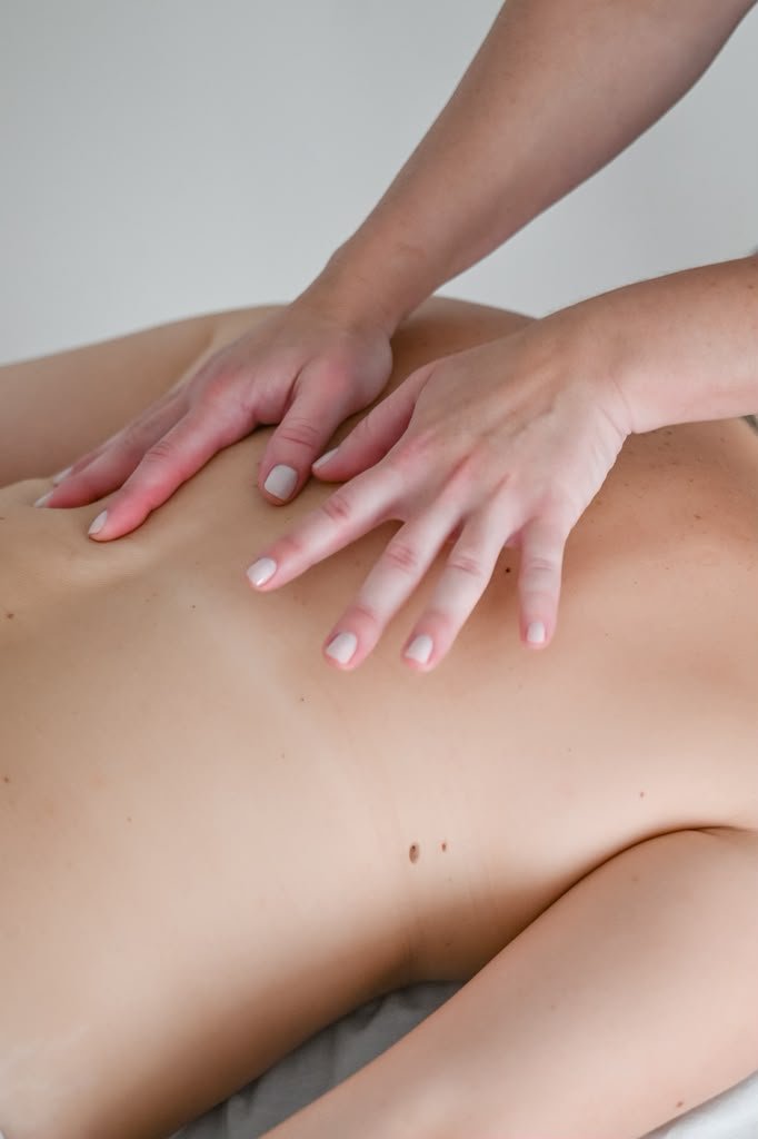 Therapist's hands applying gentle pressure to a client's back during a myofascial release session